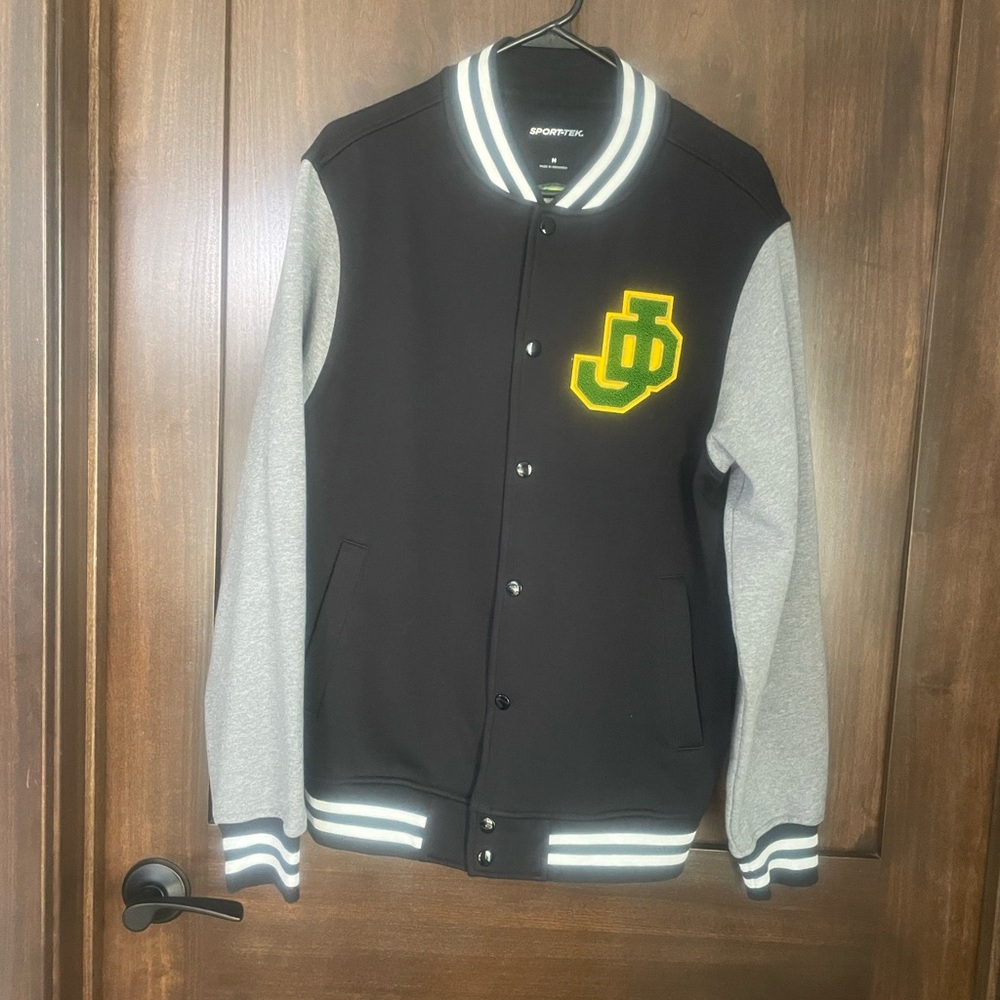 Sport-Tek Black and Gray Varsity Jacket with John Deere Logo.